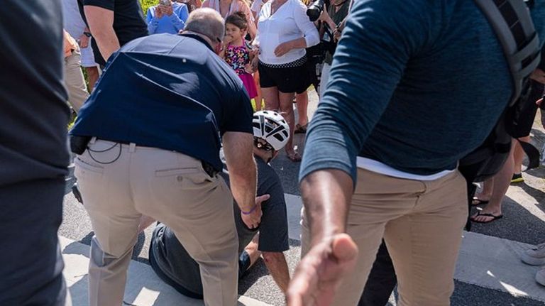 El presidente Joe Biden es asistido por sus guardaespaldas, luego de caerse de su bicicleta en Delaware.