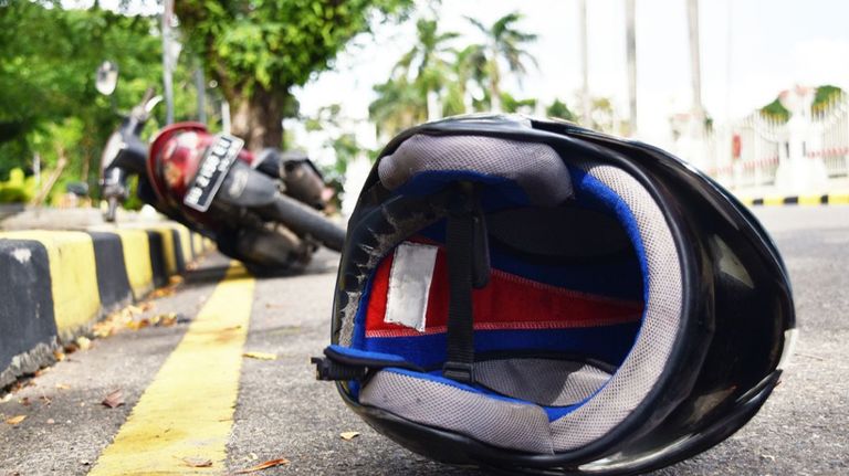 Casco en el pavimiento con moto detrás