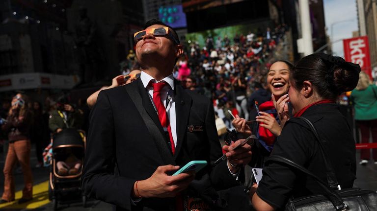 Varias personas se reúnen para ver un eclipse solar parcial, en el que la luna tapará parcialmente el sol, en Times Square, Nueva York